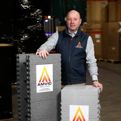 Persona in Amvic Ireland vest standing beside insulated form blocks with Amvic logo.