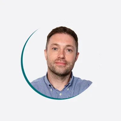 a person wearing a checkered shirt, looking at the camera against a light background.