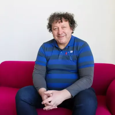 Person sitting on a bright pink sofa in a well-lit room