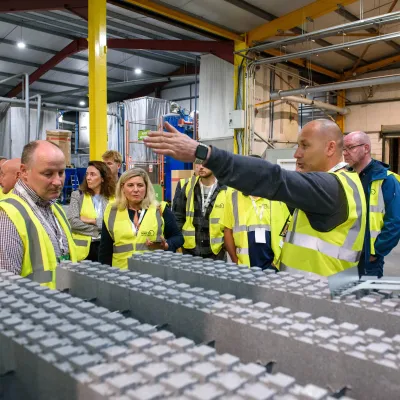 A group of people wearing high-visibility vests during a guided tour inside an industrial facility.