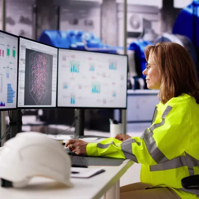 Engineer in a high-visibility jacket monitoring industrial process dashboards