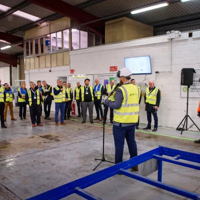 Workers in high-visibility vests gathered in an industrial warehouse space for safety training.