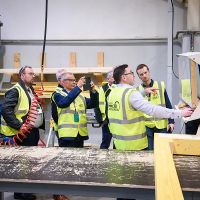Workers in yellow safety vests on a production line in an industrial facility.