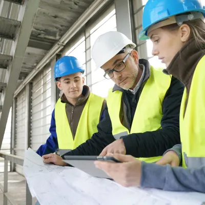 A group of engineers reviewing building plans on a construction site.