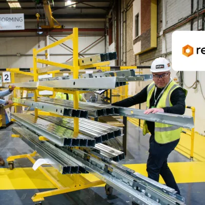 Workers in safety vests inspecting materials on yellow shelving in an industrial warehouse with Remainly logo.