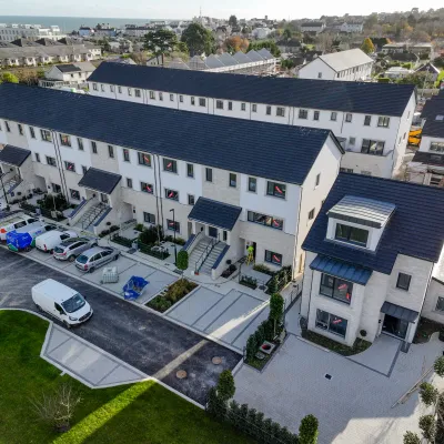 Aerial photo of newly built residential duplex houses with parked cars and landscaped surroundings.
