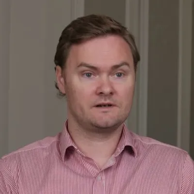 A person in a red striped shirt speaking indoors