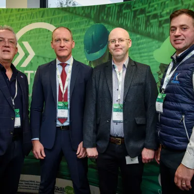 Four businessmen in suits standing together against a green backdrop with Fortinet logo.