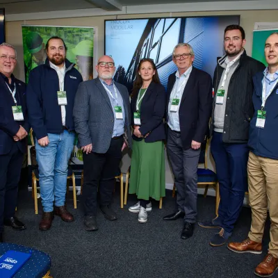 Group of people standing in a sports equipment room with jackets and athletic gear visible.