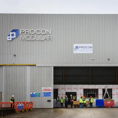 Industrial warehouse building with "MOOG" logo on corrugated metal exterior.