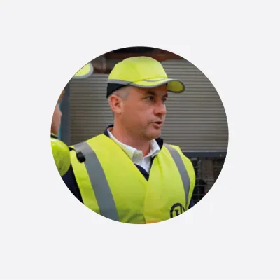 Construction worker wearing high-visibility vest and yellow safety helmet.