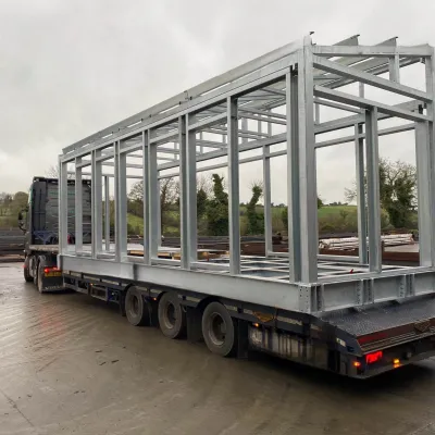 Steel frame structure secured on a flatbed trailer for transport.