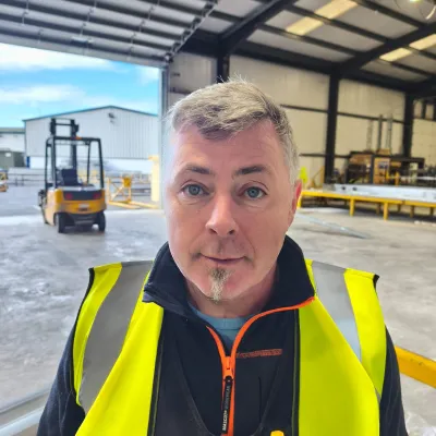 Person in high-visibility vest standing inside an industrial warehouse space.