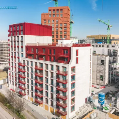 Aerial view of urban construction with red and white apartment buildings and green cranes.