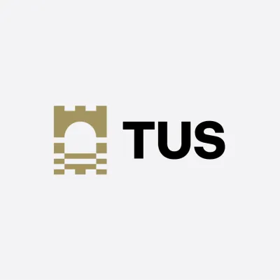 Logo of TUS featuring a gold castle tower icon next to the letters TUS in black.