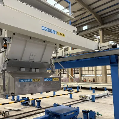 Industrial crane or lifting equipment inside a factory or warehouse with blue structural elements.