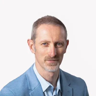 Professional portrait of person with short hair wearing a blue suit and light shirt.