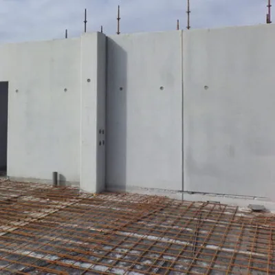 Tall concrete wall sections standing upright at a construction site with rebar visible.