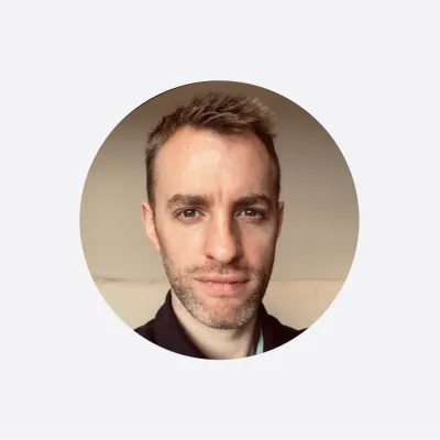 Portrait photograph of a person with short hair against a neutral background.