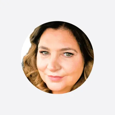 Circular profile photograph of a person with long wavy hair and subtle makeup.