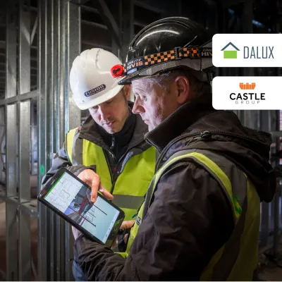 Construction workers examining digital plans inside a building site with Dalux and Castle logos.