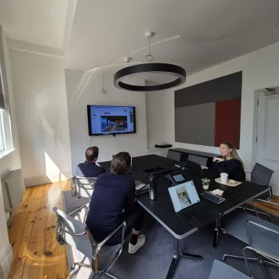 Several people seated at a modern conference table in a bright office space with a circular pendant light.