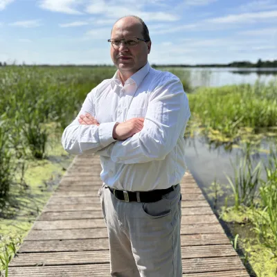 Person in white shirt standing on a wooden pathway surrounded by wetland vegetation.