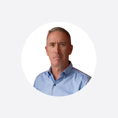 Middle-aged man in a light blue shirt, serious expression, circular cropped portrait photo.