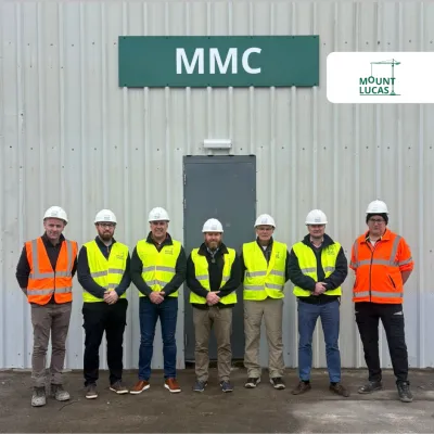 Seven people in high-visibility vests standing in front of a green MMC building.