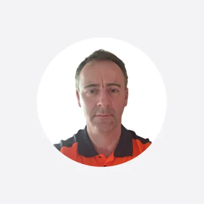 Man in an orange high-visibility shirt, circular cropped headshot photo.