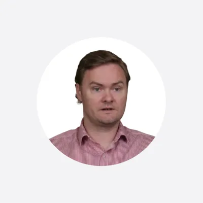 Circular portrait photo of a young man with brown hair wearing a pink button-up shirt.