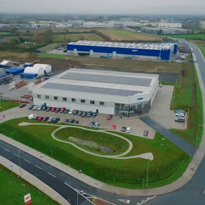 Aerial view of a modern industrial or logistics park with large blue warehouses and well-maintained roads.