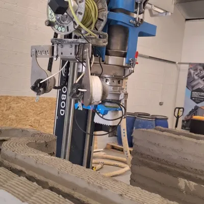 Blue industrial drill press machine in a workshop setting.