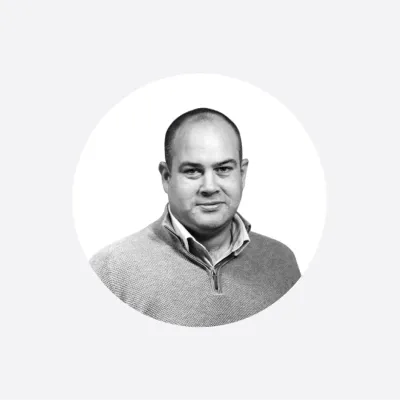 Black and white portrait photograph of a middle-aged man in a light sweater, circular crop.