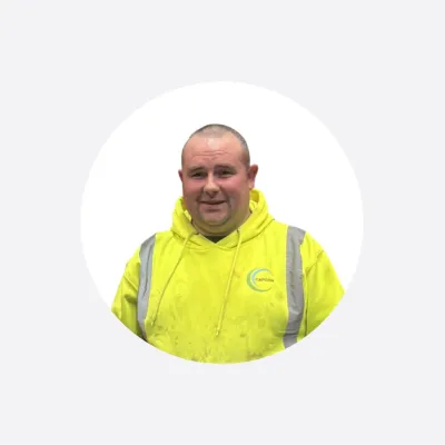 Man wearing a yellow high-visibility safety jacket, smiling, circular cropped photo.