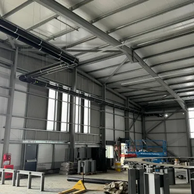 Interior of a large industrial warehouse with steel beams, high ceilings, and machinery.