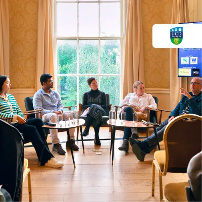Five people seated in a semicircle having a panel discussion in an elegant, warmly lit room.