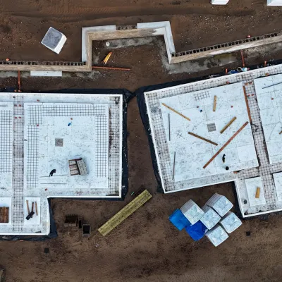 Aerial view of two concrete building foundations under construction on a dirt lot.