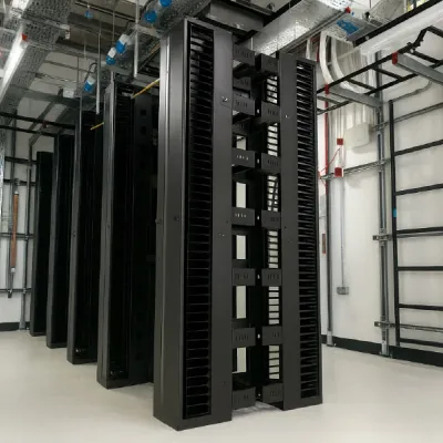 Rows of tall black server racks in a clean, organized data center with cable management.