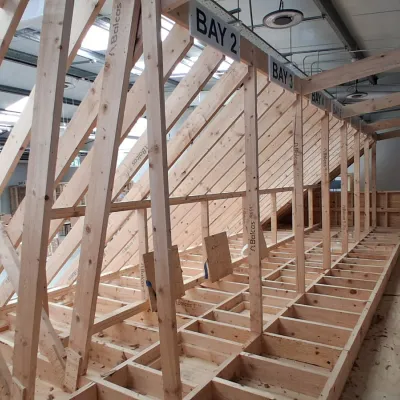 Wooden roof trusses and framing under construction inside a large building.