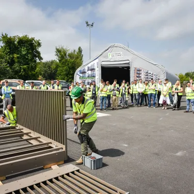 Workers in safety vests and hard hats gathered outdoors at an industrial facility during a demonstration.