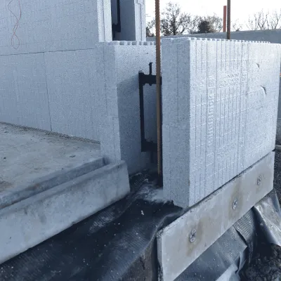 Concrete block wall construction at a building site, with exposed foundation and debris.