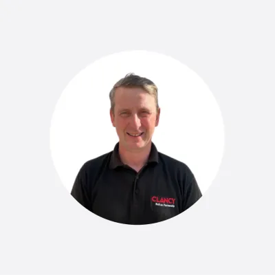 Man in black polo shirt with company logo, smiling, circular cropped photo.