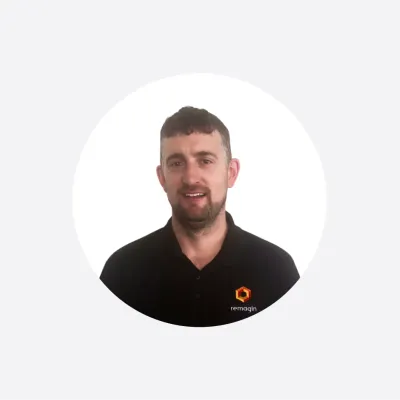 Professional headshot of a man in a black polo shirt with a company logo, circular crop.