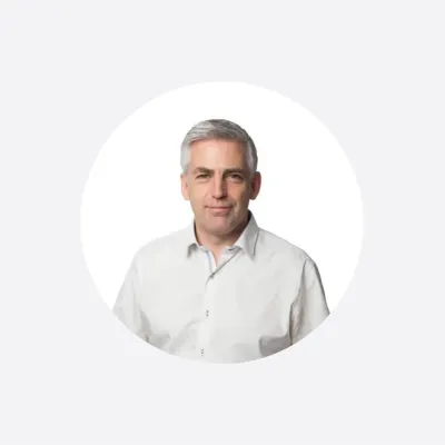 Professional headshot of a middle-aged man in a white shirt, circular crop.
