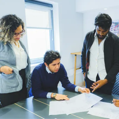Three colleagues reviewing documents together at a conference table in an office.
