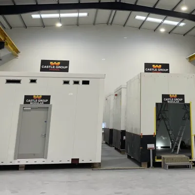Interior of a manufacturing facility showing large prefabricated modular units at different stages of production.