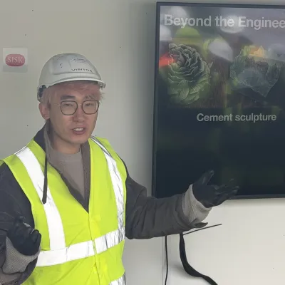 Man in hard hat and safety vest pointing at a screen displaying "Cement sculpture."