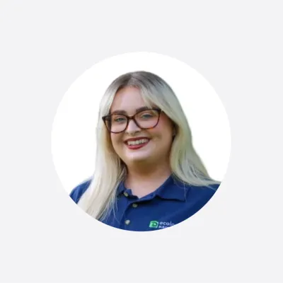 Smiling woman with long blonde hair and glasses, wearing a navy blue polo shirt, circular crop photo.