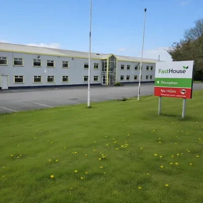 Two-story yellow office building with a green lawn and a red company sign in front.
